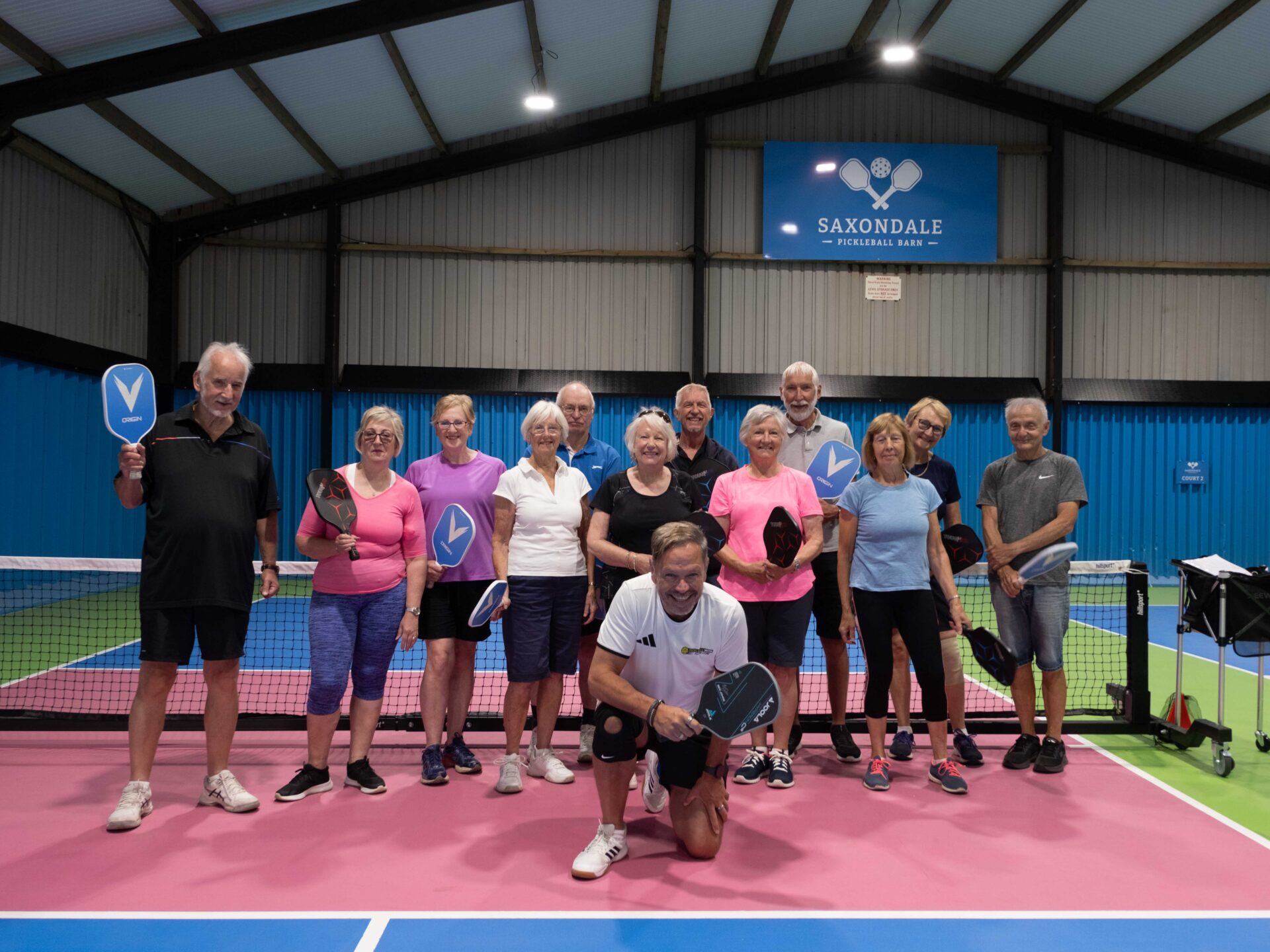 Group of people smiling with pickleball bats in hand